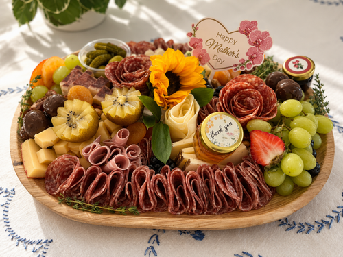 Mother's Day charcuterie board with fruits, cheeses, and flowers on a decorative tablecloth.